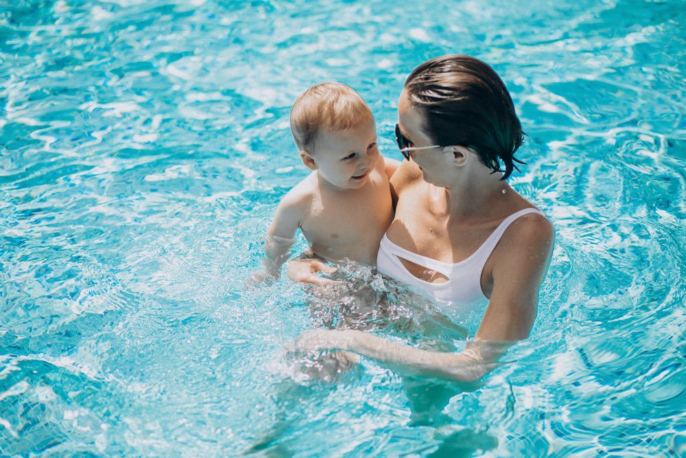 eine Mutter mit ihrem Baby auf dem Arm im Schwimmbecken Image